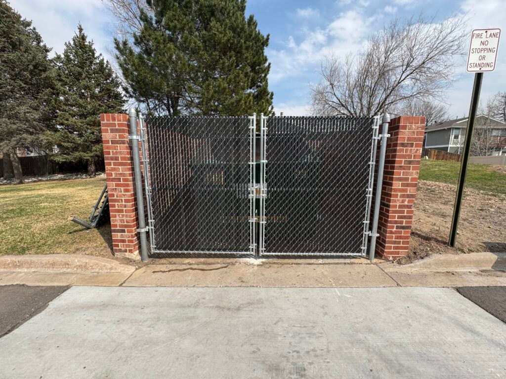 Double chain link driveway gates between brick posts